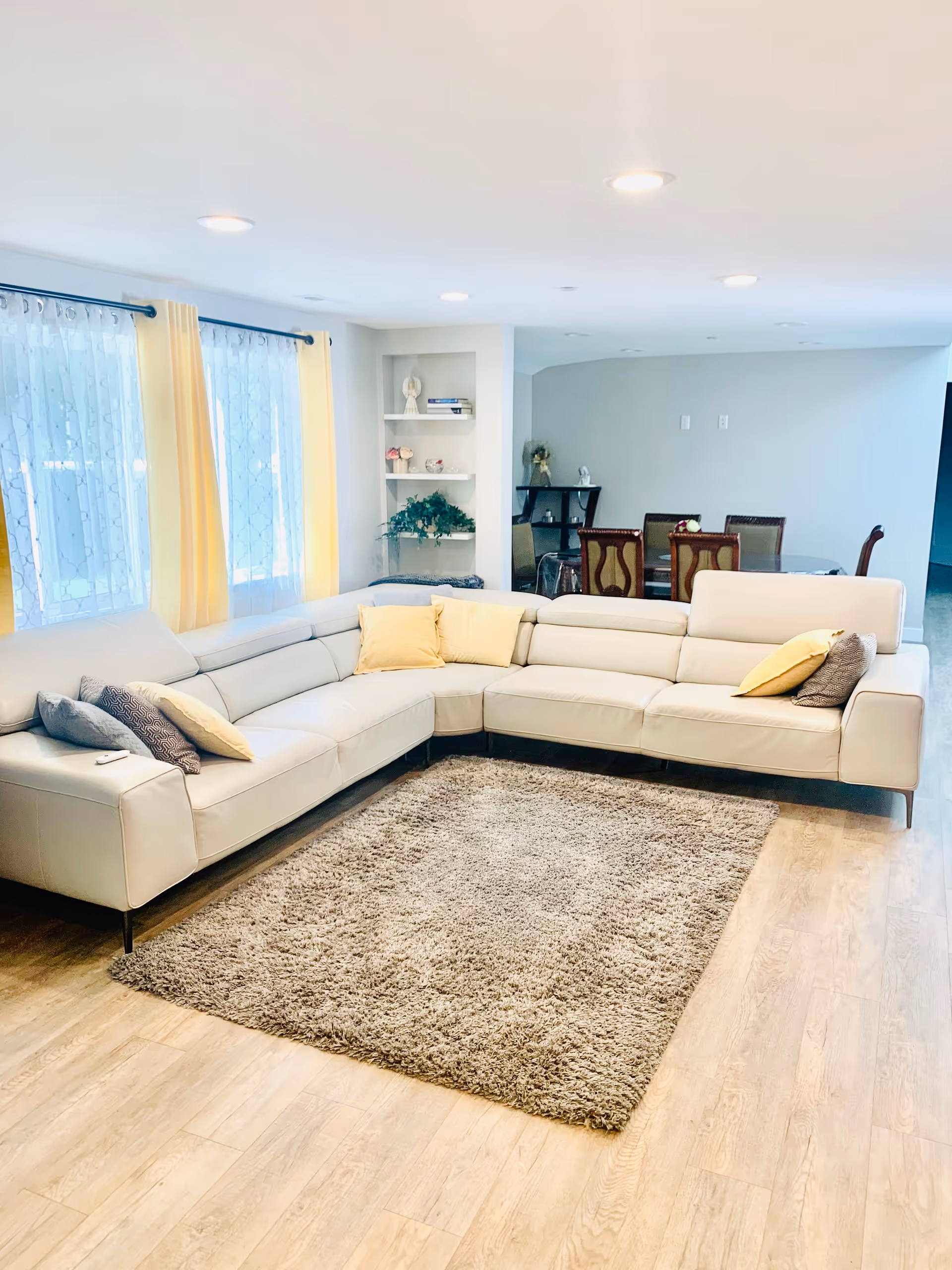 Bright living room with a white sectional sofa, yellow curtains, and a plush rug.