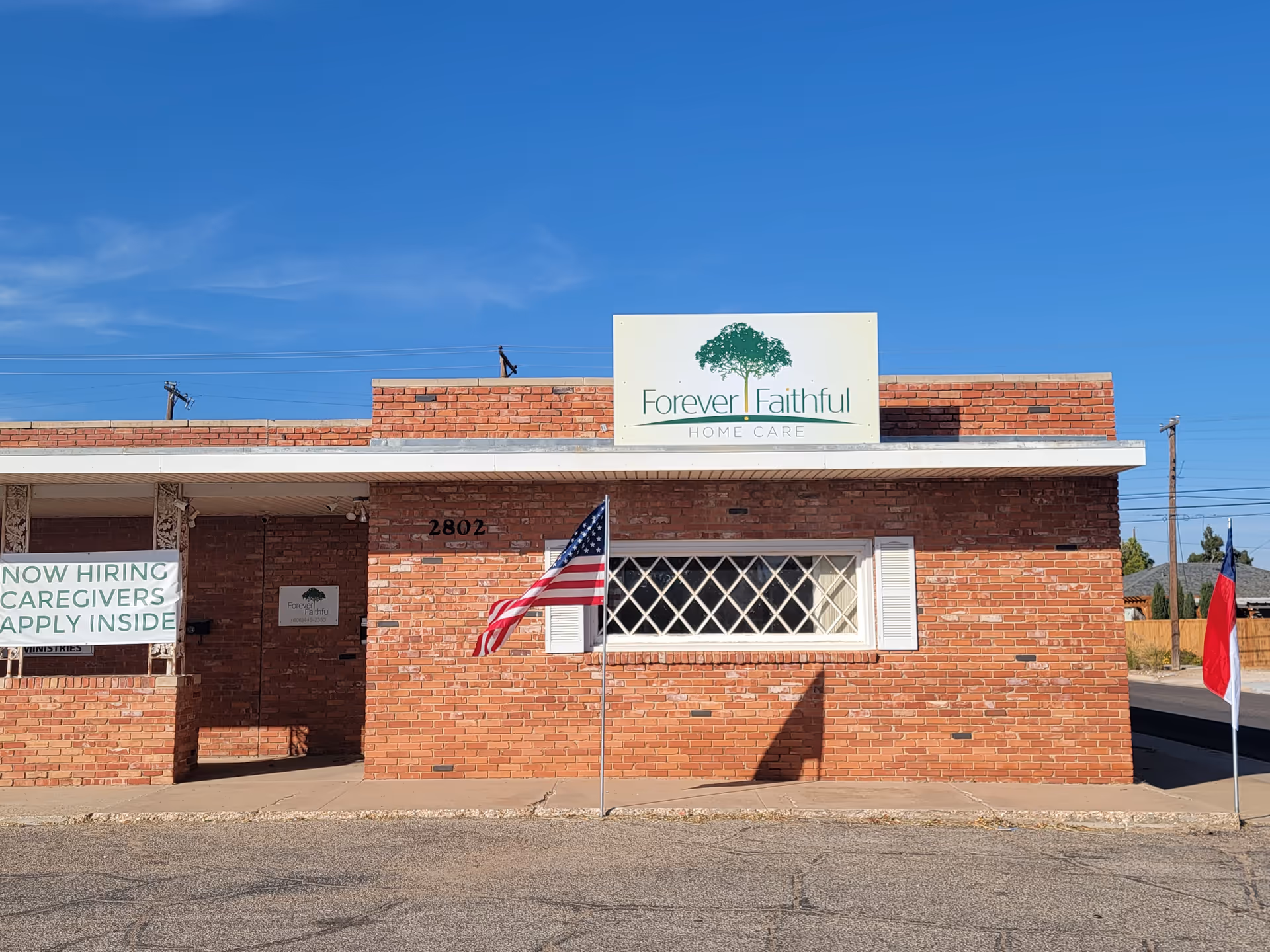 Brick building front with Forever Faithful Home Care sign and flags.