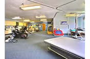 Interior rehabilitation gym at Skyline Transitional Care Center with exercise equipment and treatment tables.