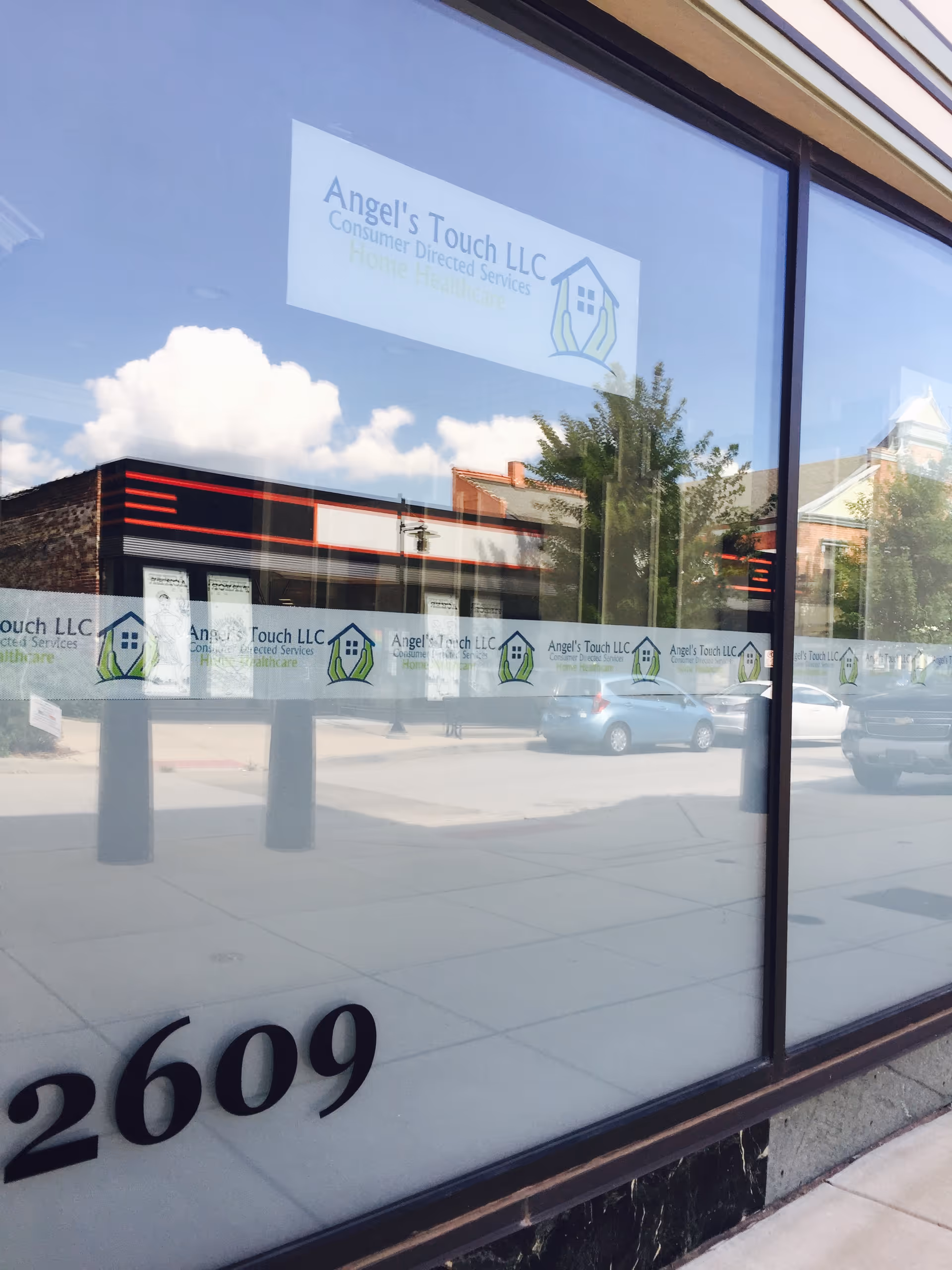 Storefront window displaying Angel's Touch LLC signage with street reflections.