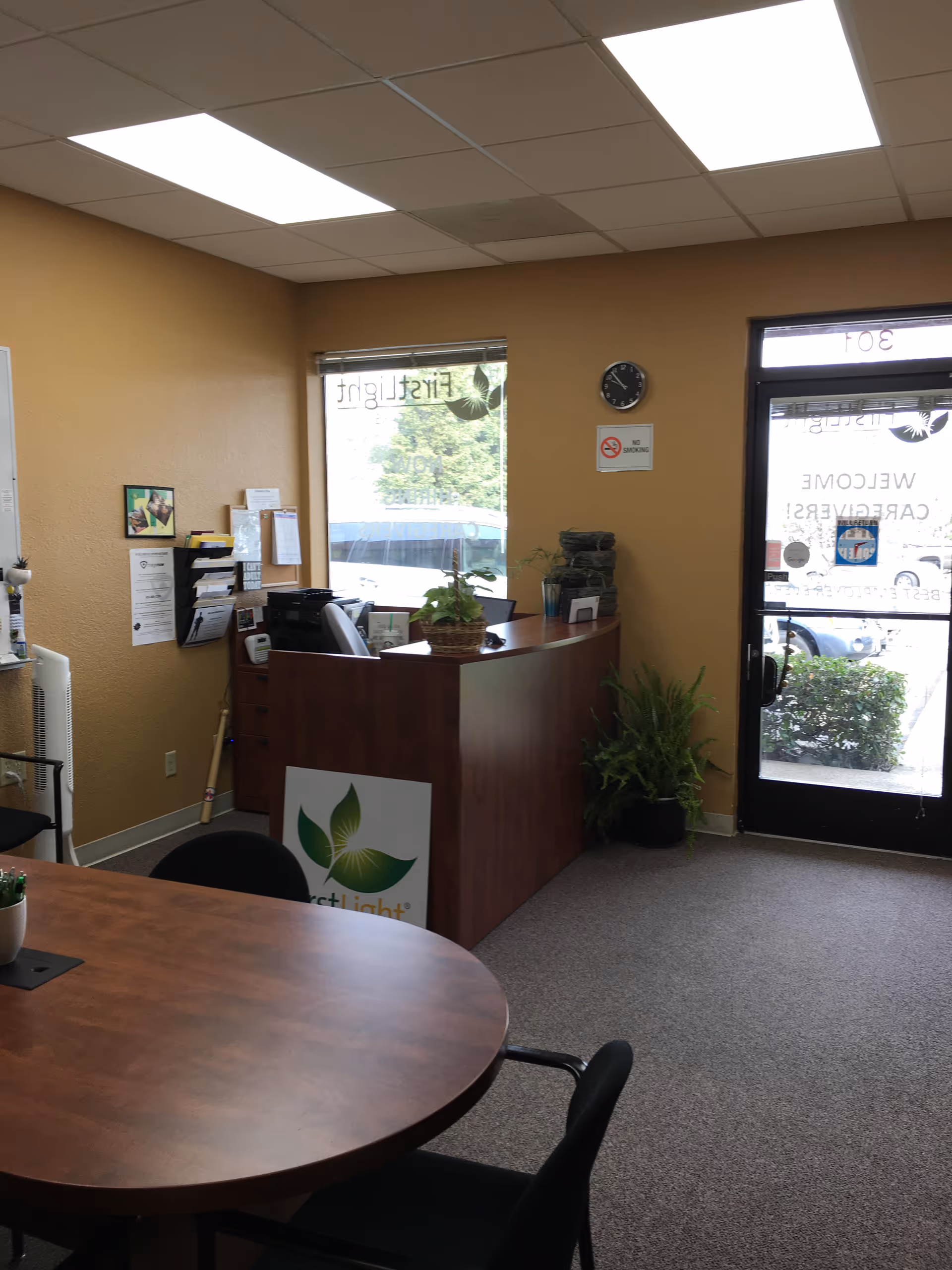 Reception desk in a warm interior with plants and a round table.