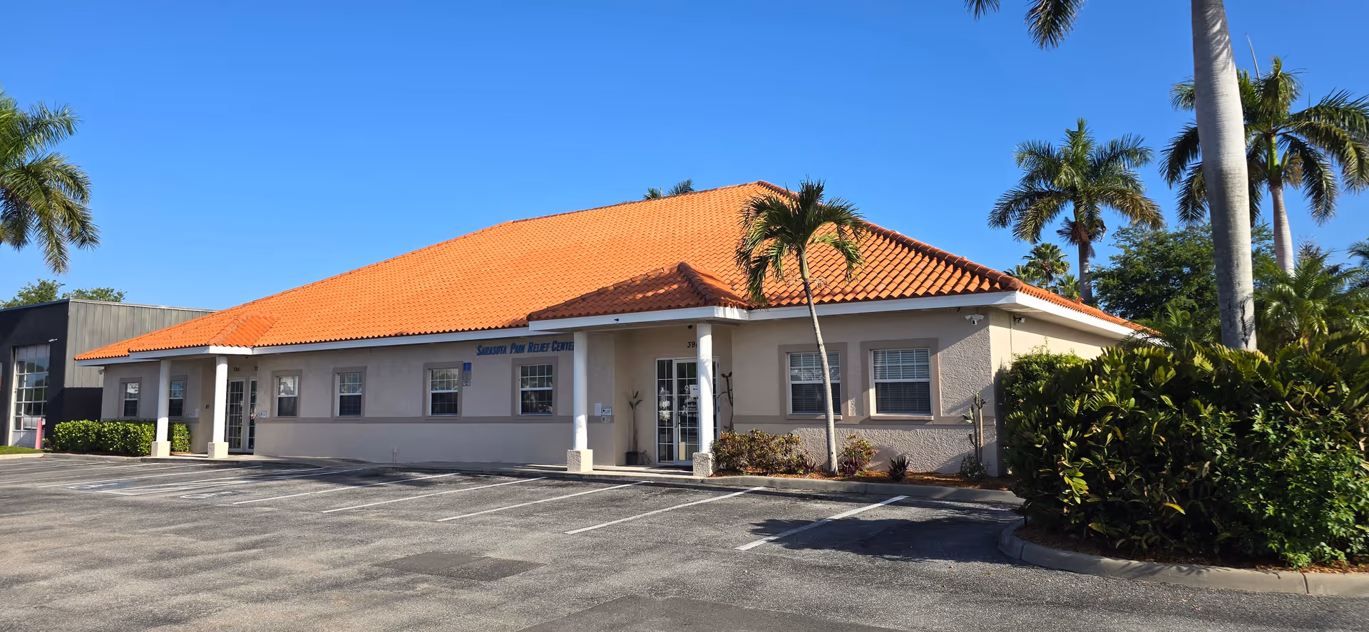 Exterior of a single-story building with orange-tiled roof and palm trees.