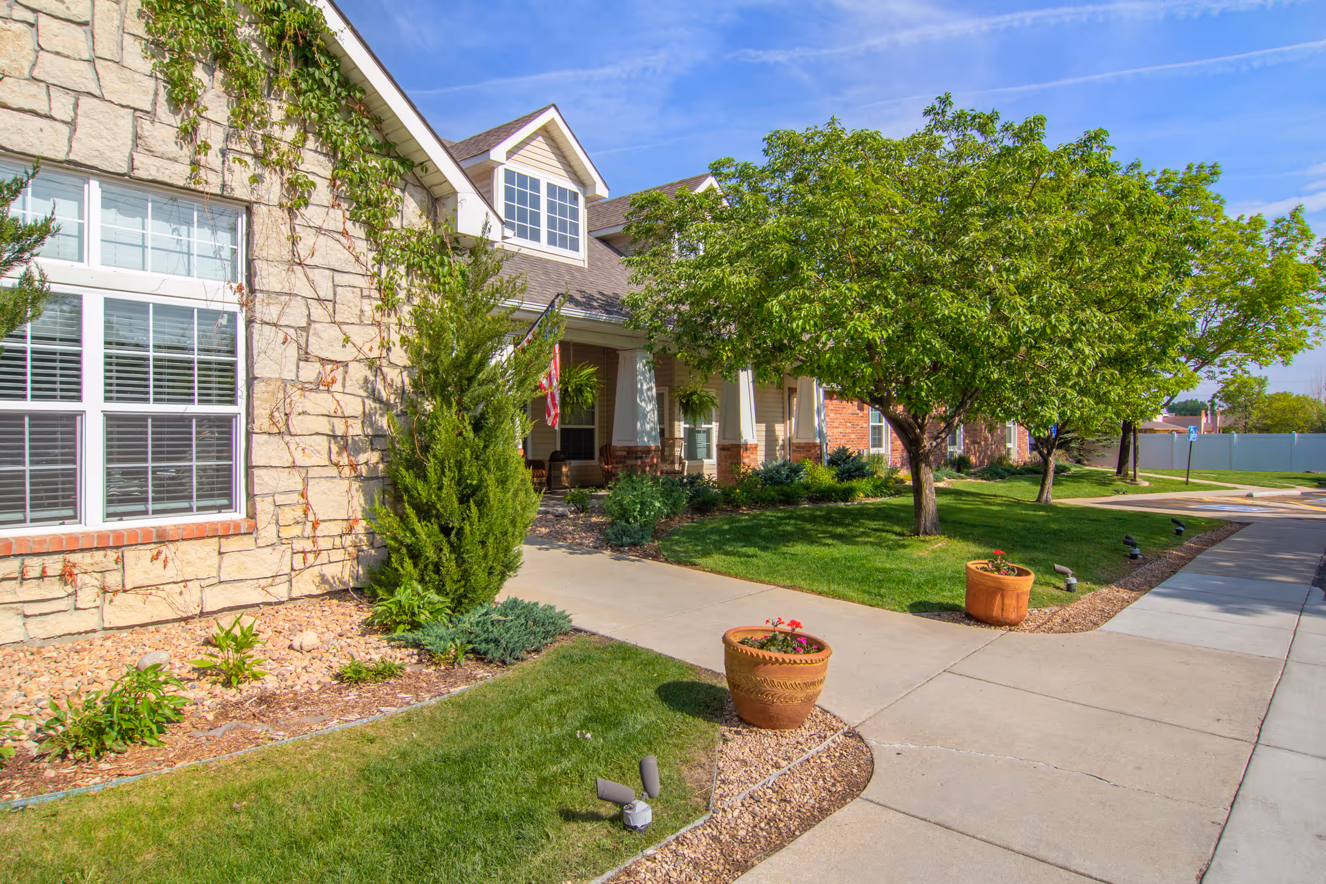 Brookdale Longmont exterior showing stone facade, front lawn, trees, and walkway to the entrance.
