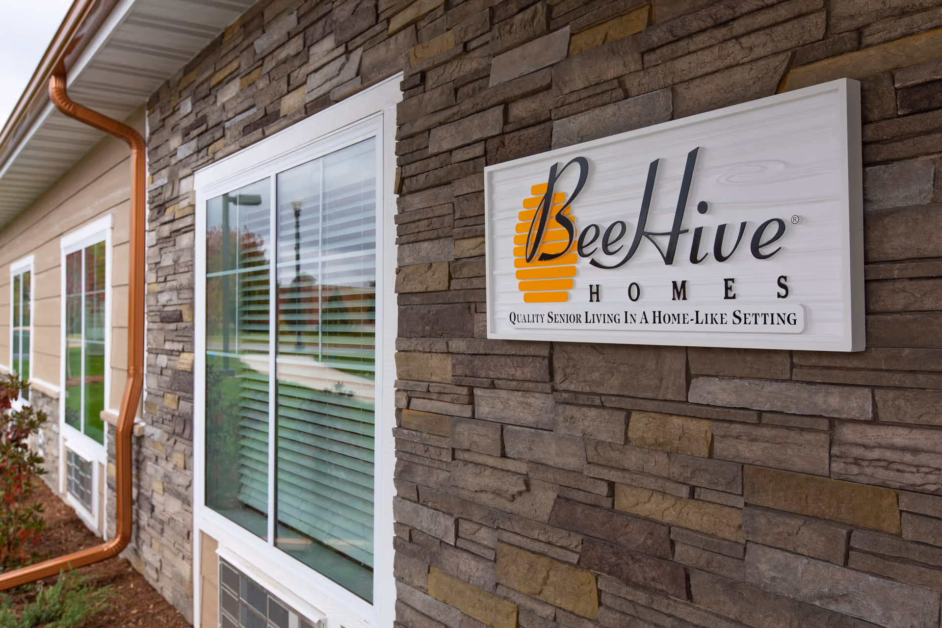 Stone-clad exterior with a Beehive Homes sign on the front wall
