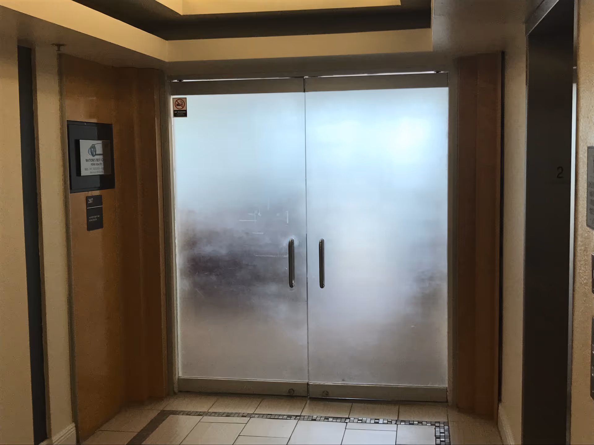 Interior hallway with frosted double doors and tiled floor in a senior living facility.