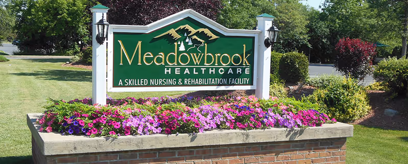 Exterior Meadowbrook Healthcare sign framed by a colorful flower bed.