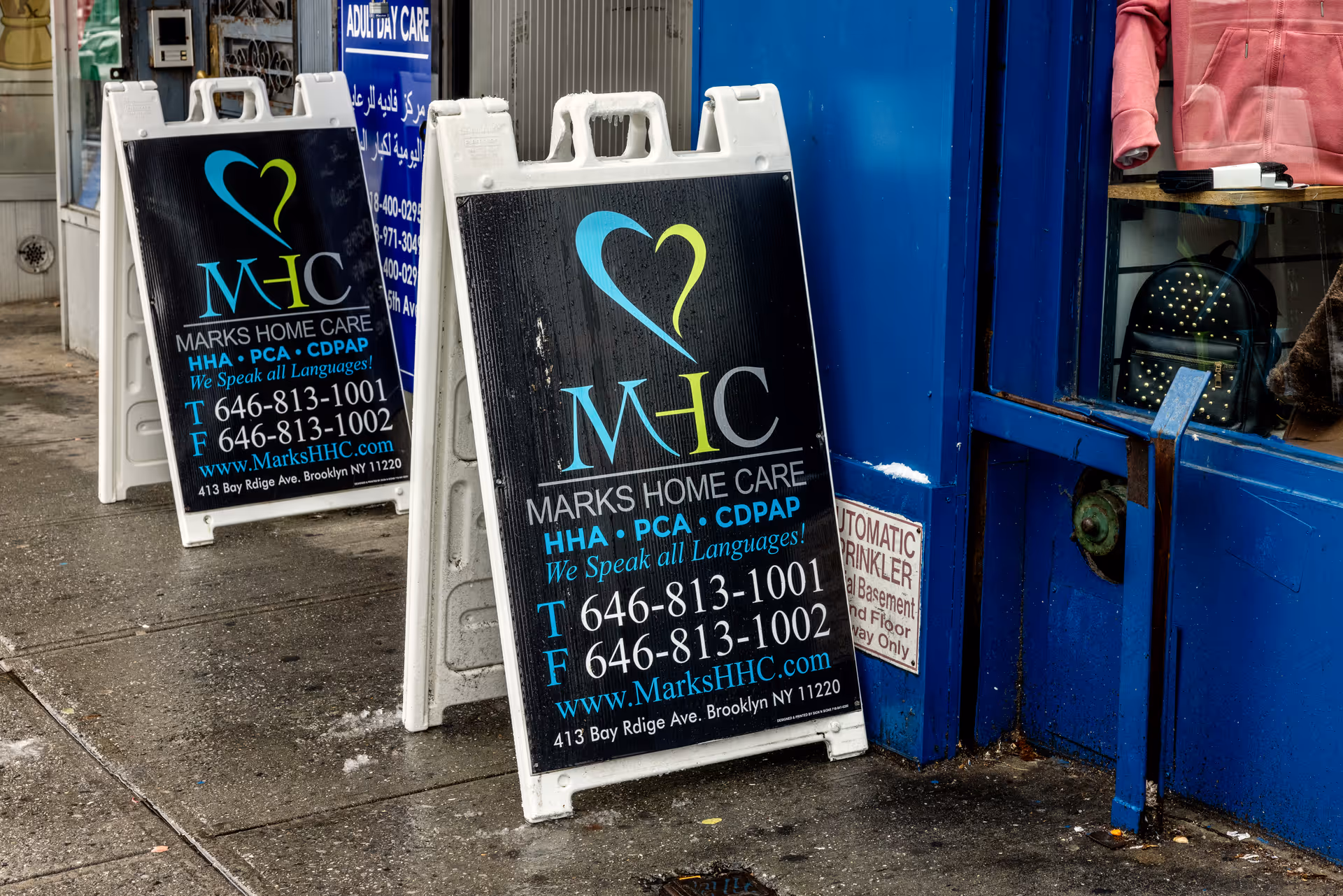 Outdoor sidewalk with two A-frame signs advertising Marks Home Care Agency.