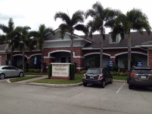 Exterior view of CardioFlex Therapy senior living facility with palm trees and parked cars.