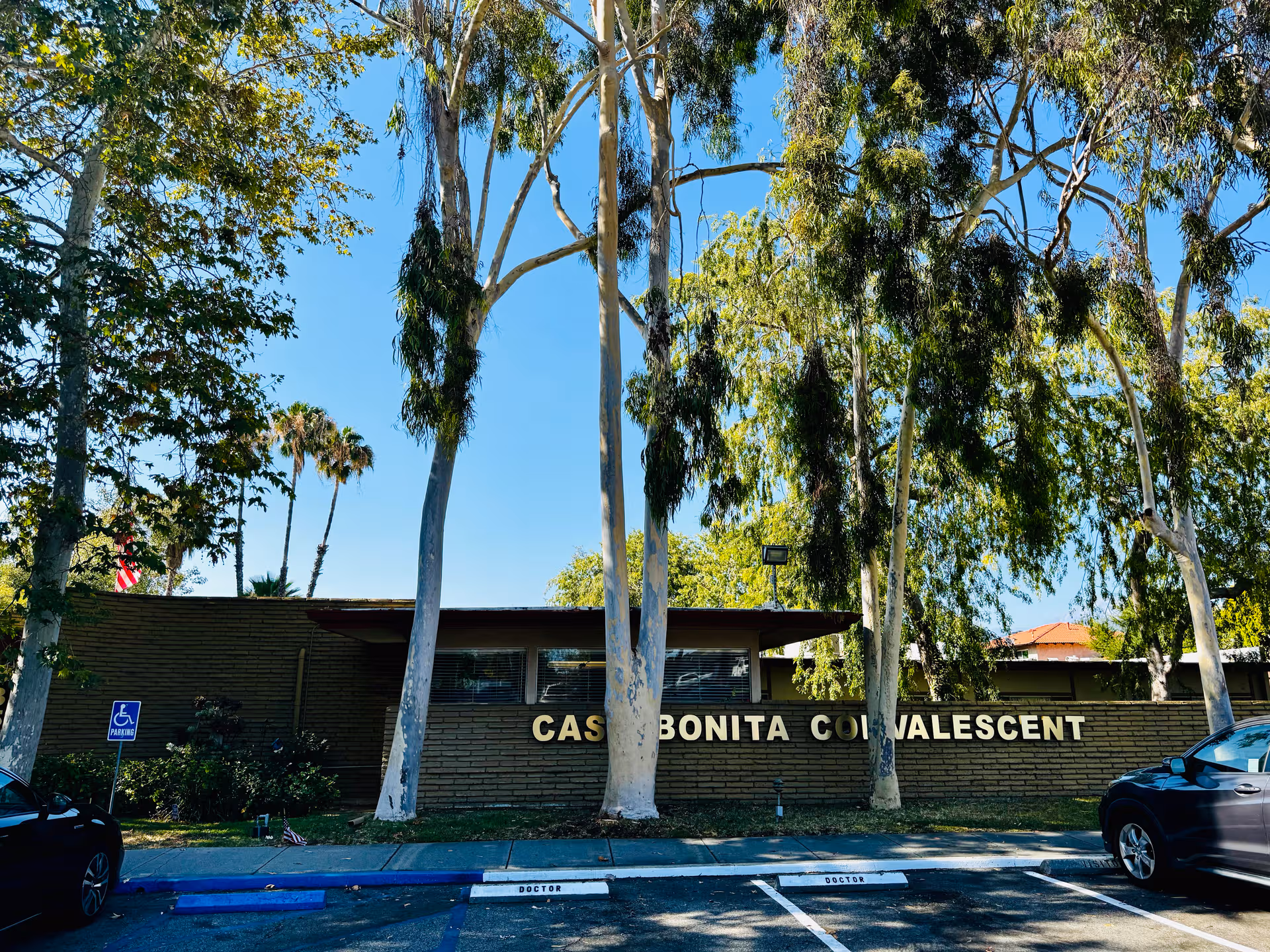 Front view of Casa Bonita Convalescent Hospital with trees, parking, and sign.