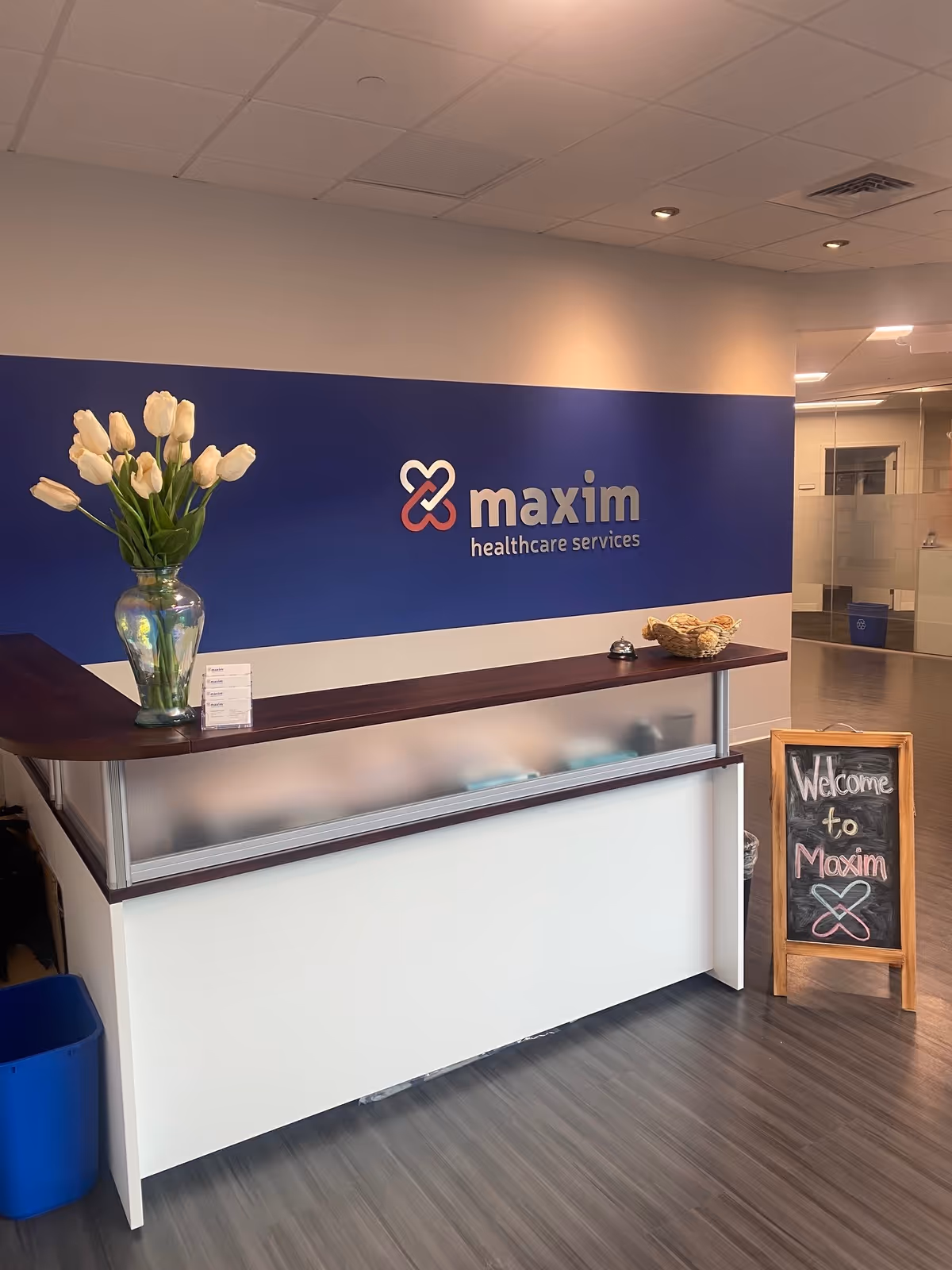 Reception desk with Maxim Healthcare signage and tulips in a bright lobby.
