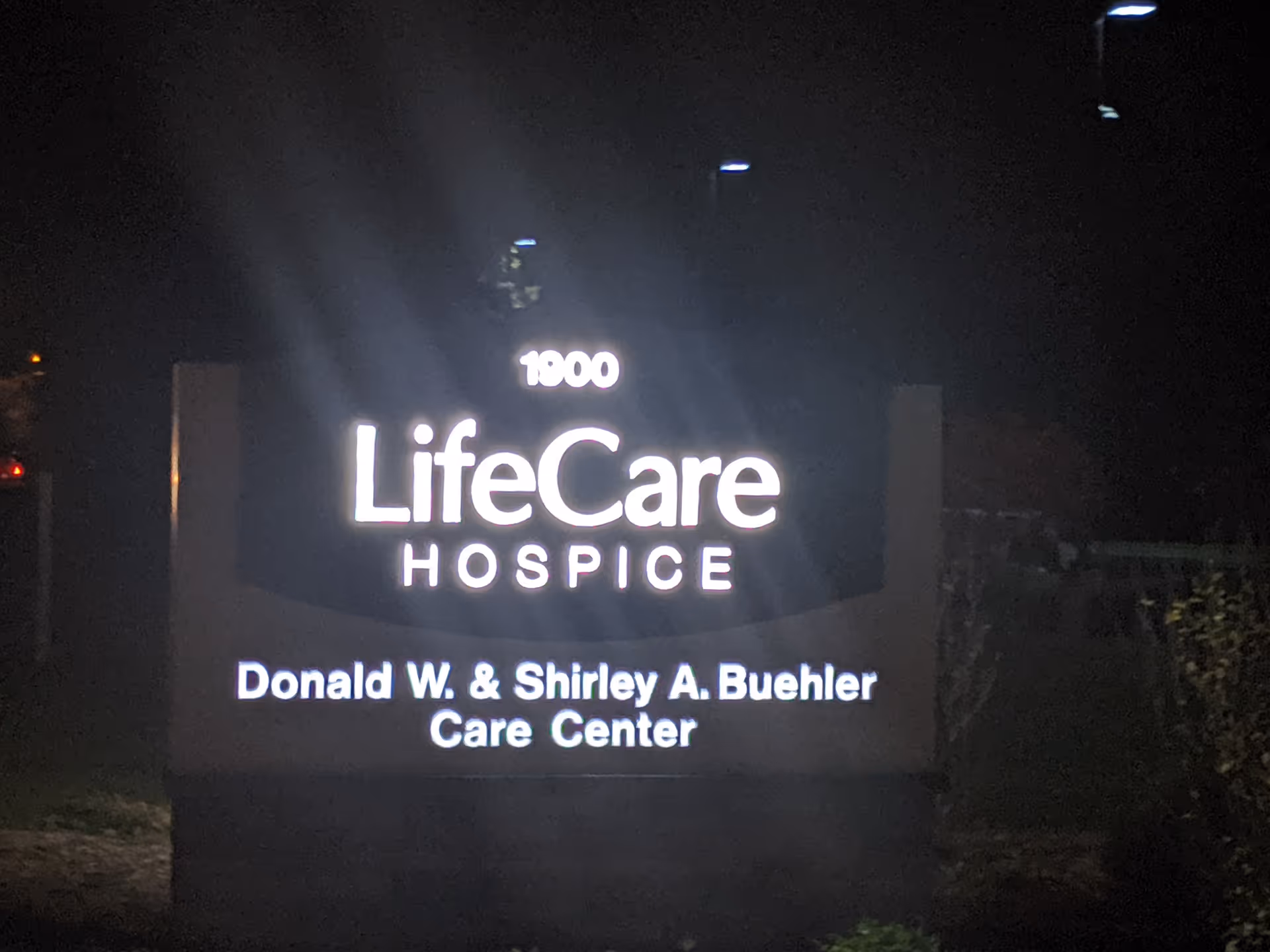 Nighttime exterior sign reads LifeCare Hospice and Donald W and Shirley A Buehler Care Center.