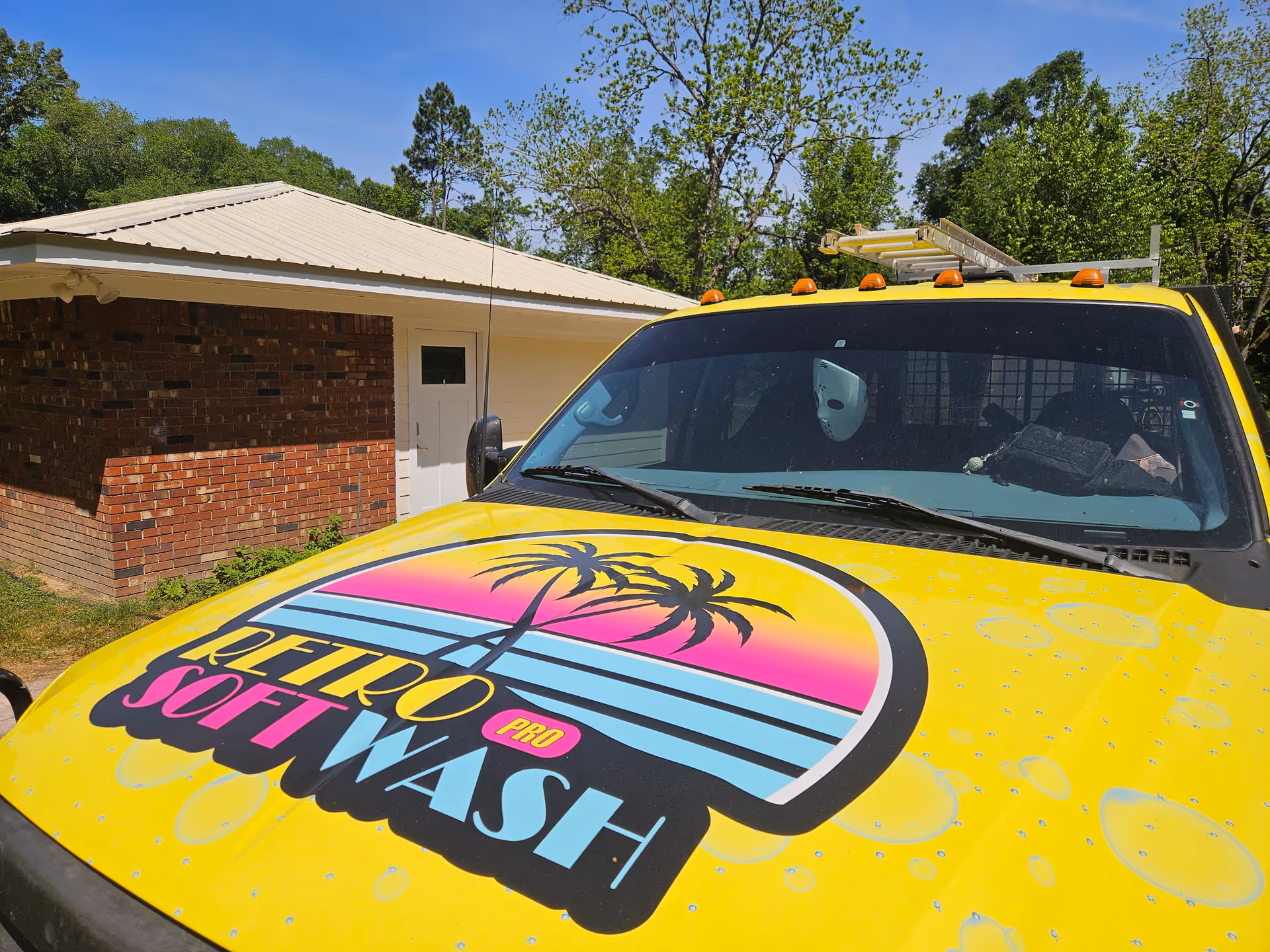 Bright yellow van with retro logo parked outside a brick, single-story building.