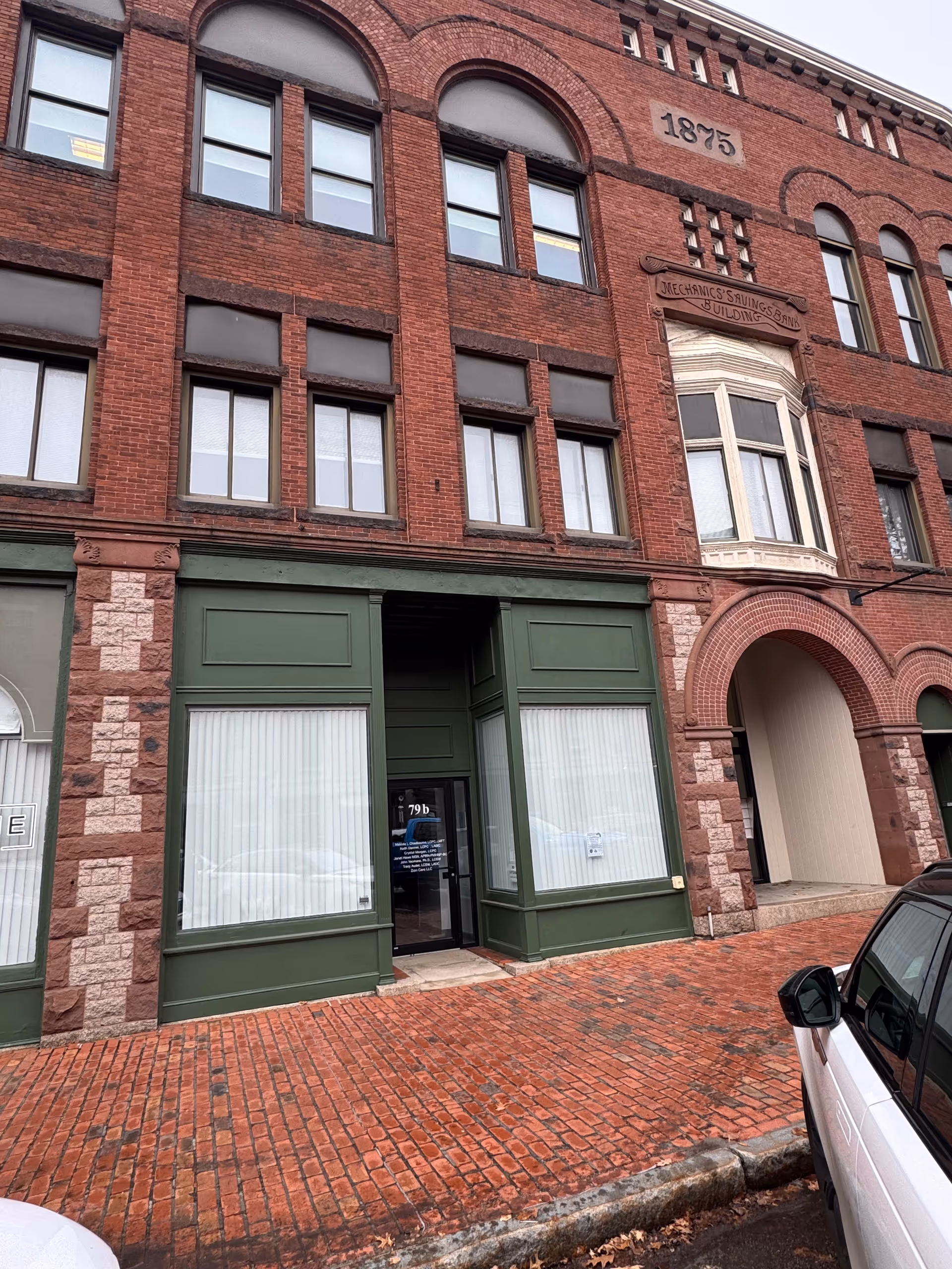 Historic red brick building facade with arched windows and green storefront entrances.