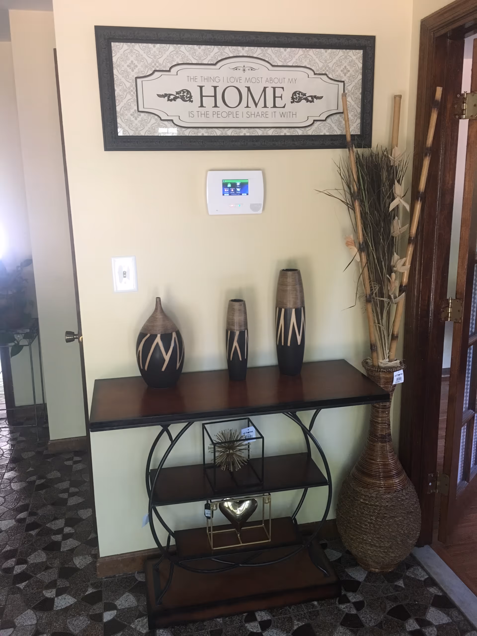 Hallway foyer with a console table, decorative vases, and a framed sign on a pale wall.