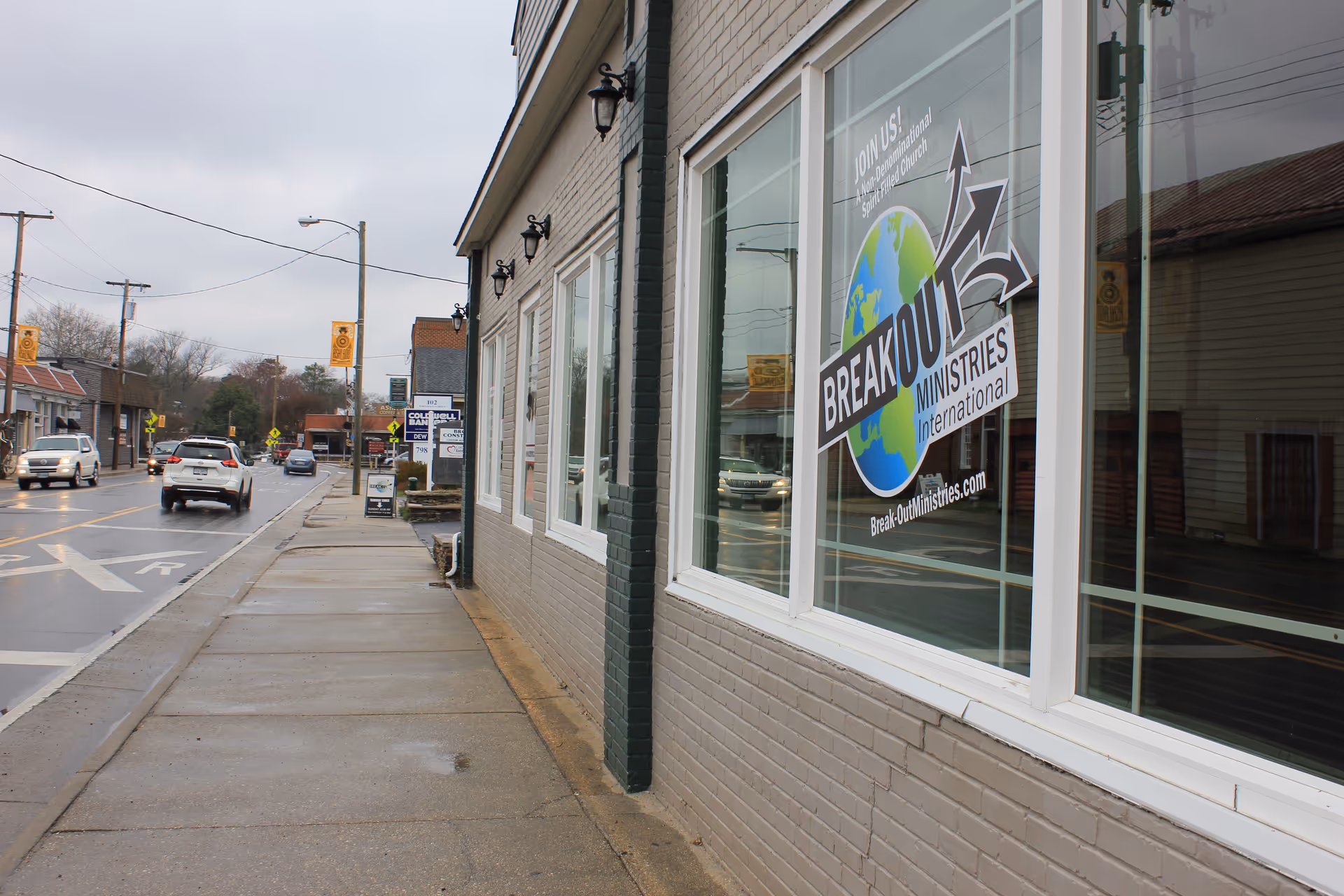 Exterior street view of a storefront with large windows and a Breakout Ministries sign.