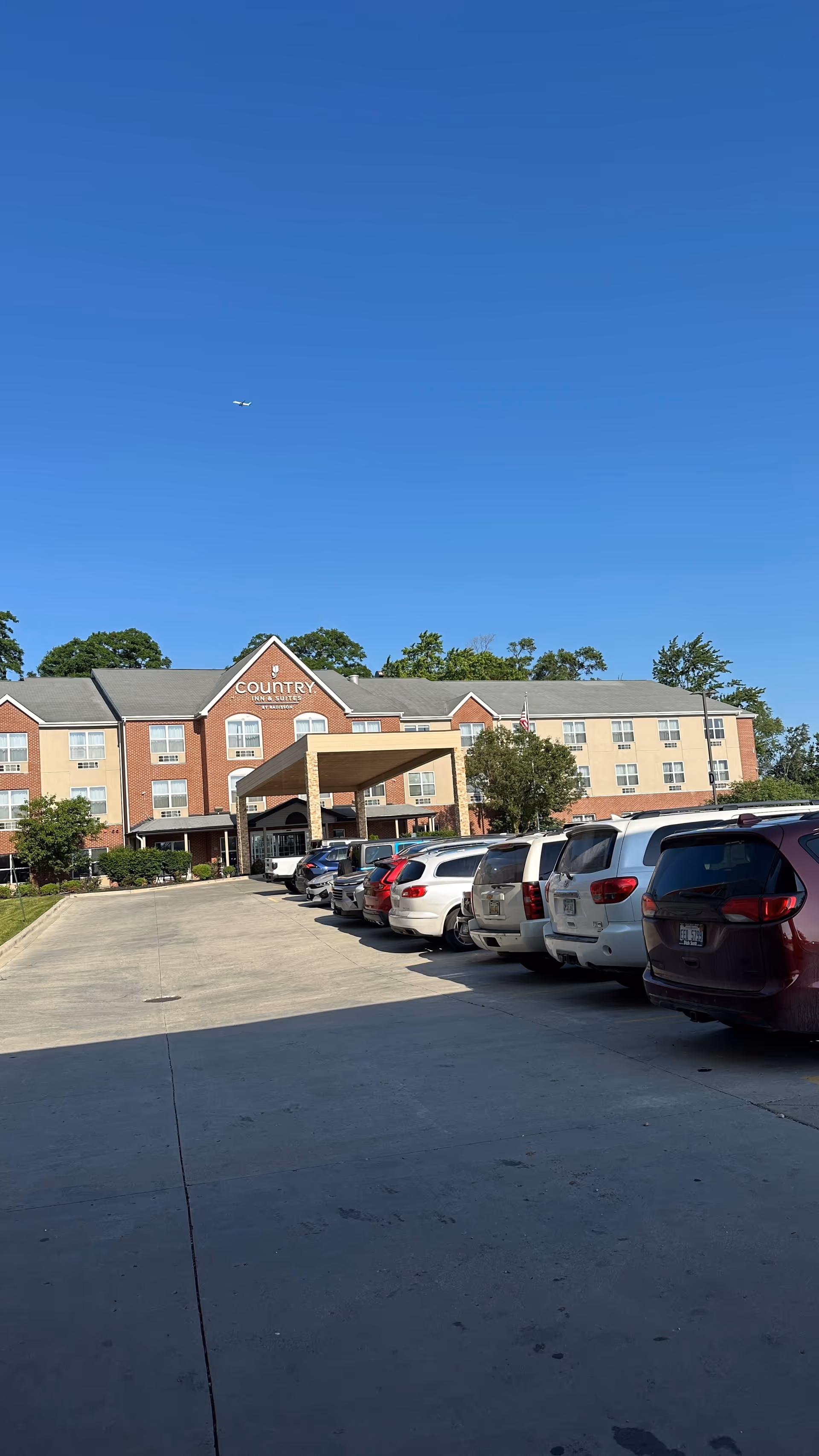 Exterior view of a senior living facility with a covered entrance and parked cars.