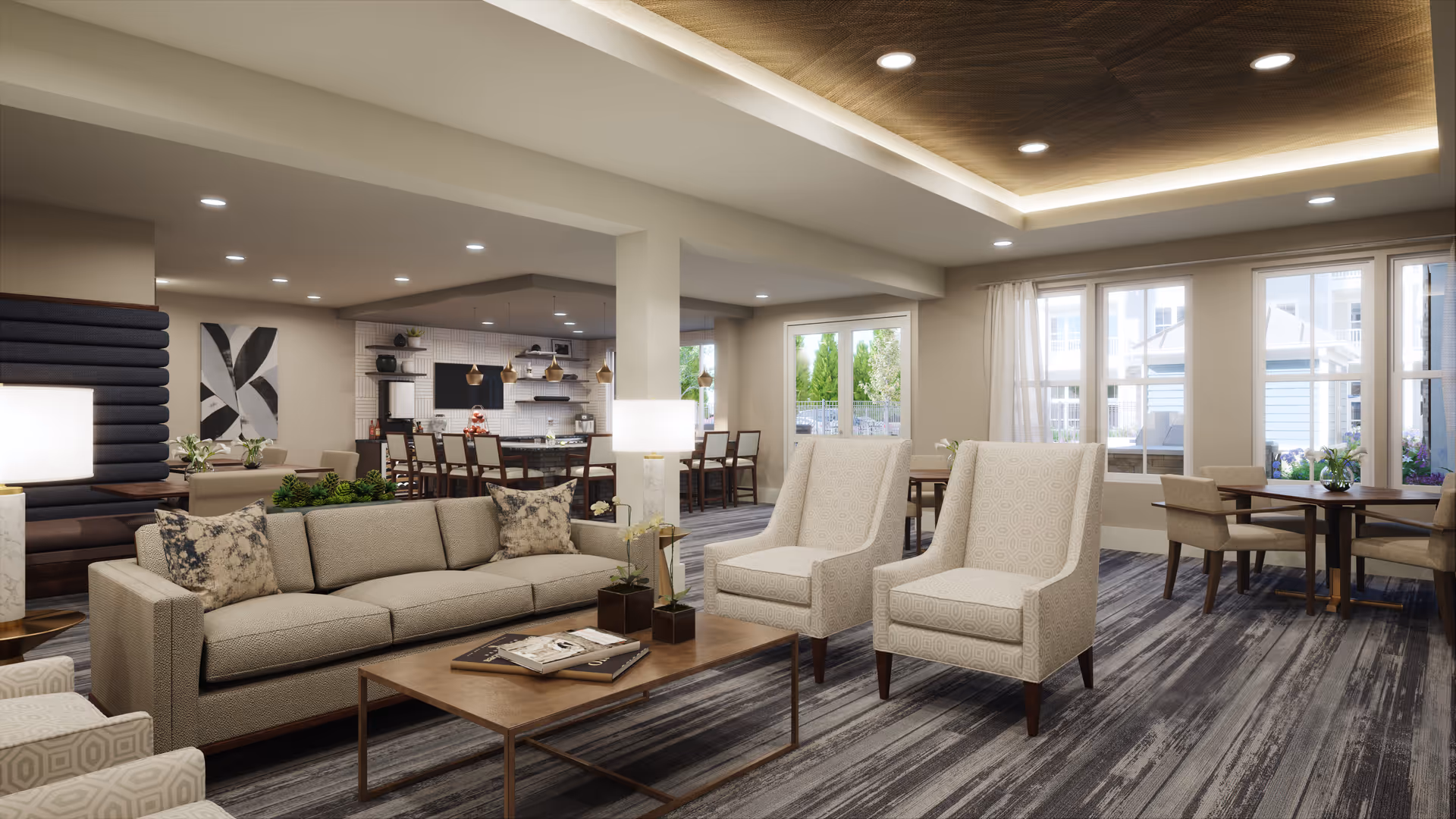 A spacious and modern living room area in a senior living facility with a beige sofa, two patterned armchairs, a wooden coffee table with books and plants, and several dining tables and chairs near large windows letting in natural light. The ceiling has recessed lighting and a decorative wooden panel. In the background, there is a kitchen area with bar stools and pendant lights.