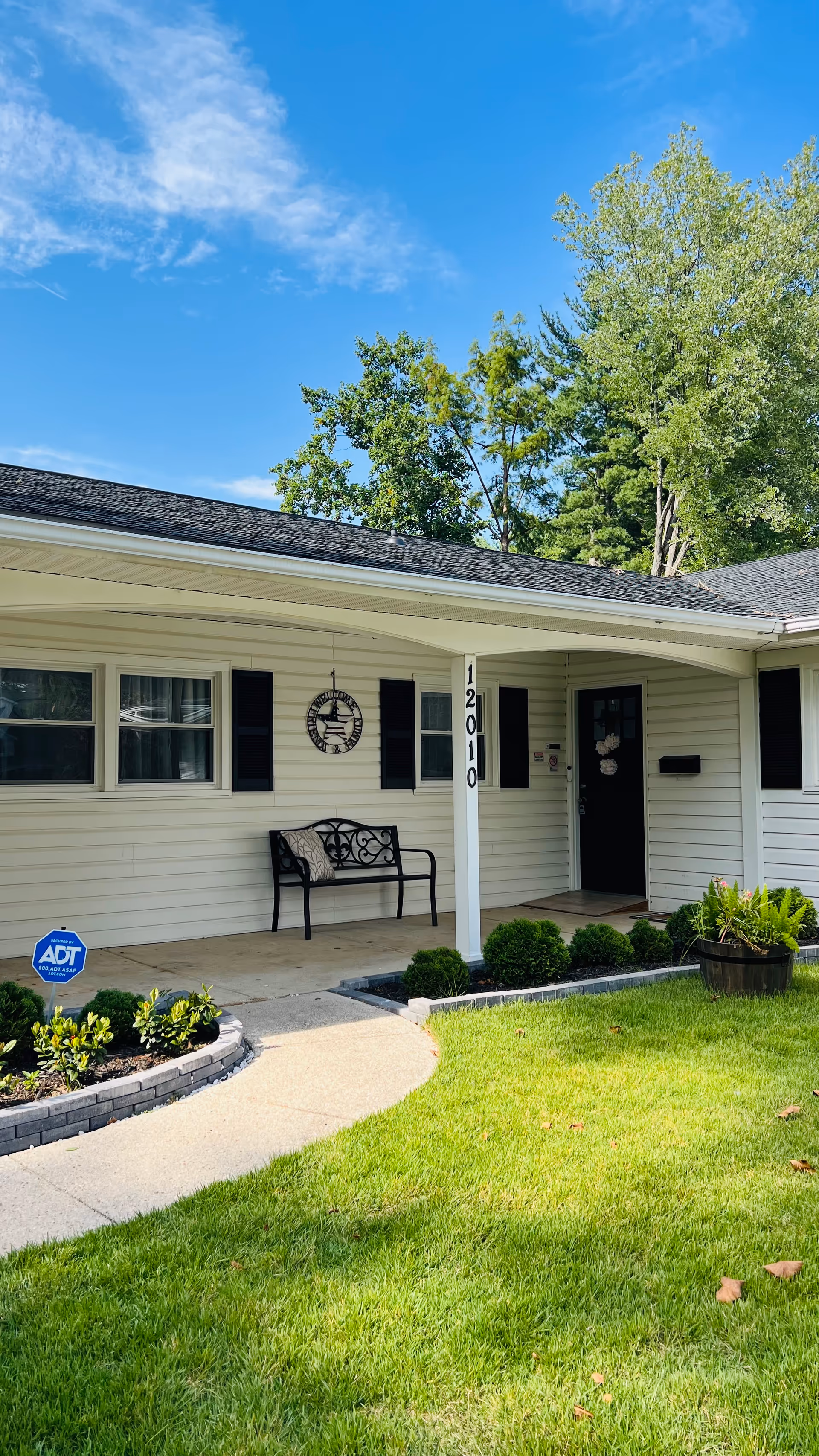 Front view of a single-story senior living house with a bench and landscaped yard.