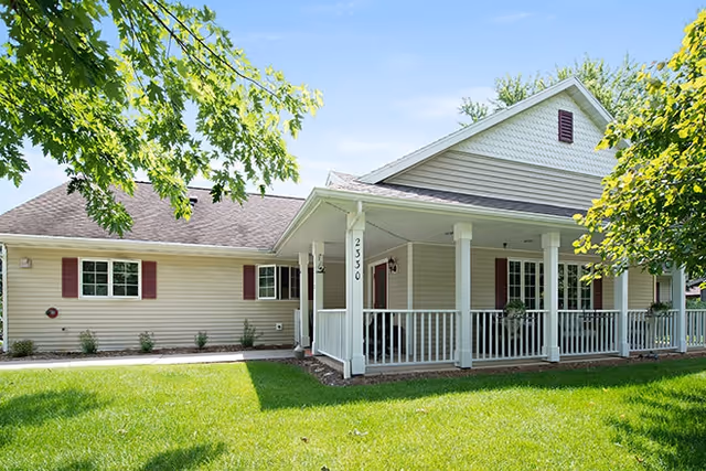 Aperion Care Lincoln exterior: single-story facility with white porch, railings, and green lawn.