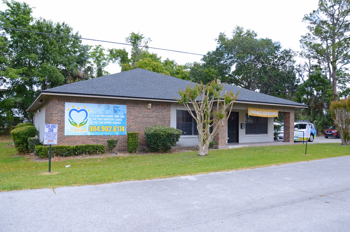 Brick one-story building with a Grand Opening banner and lawn signage.