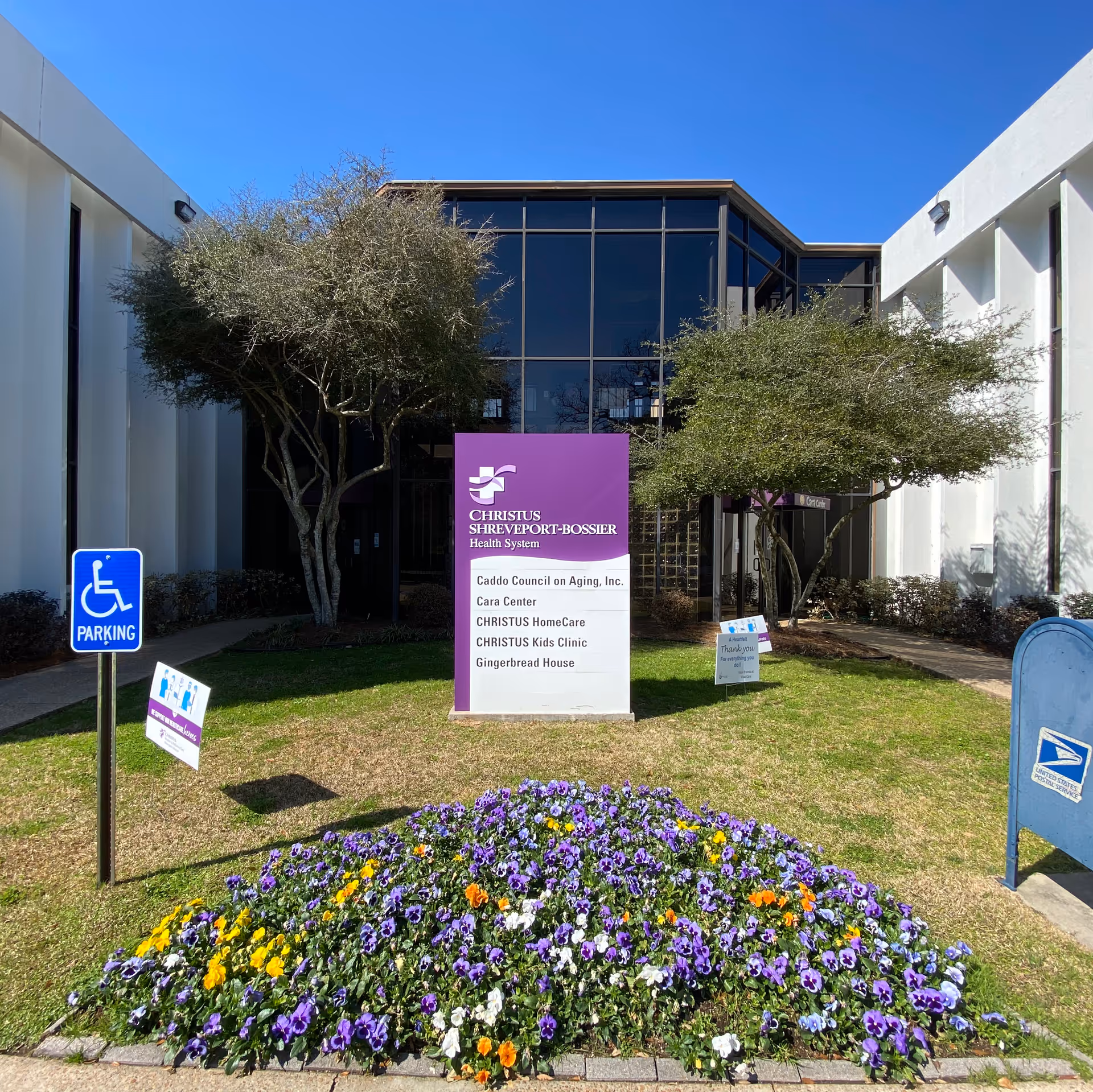 Exterior view of the CHRISTUS Shreveport-Bossier entrance with a purple sign and flowers.