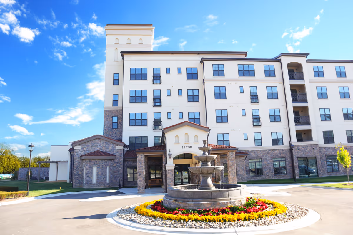 Exterior view of Trevi Vibrant Senior Living building featuring a central fountain and circular flower bed.