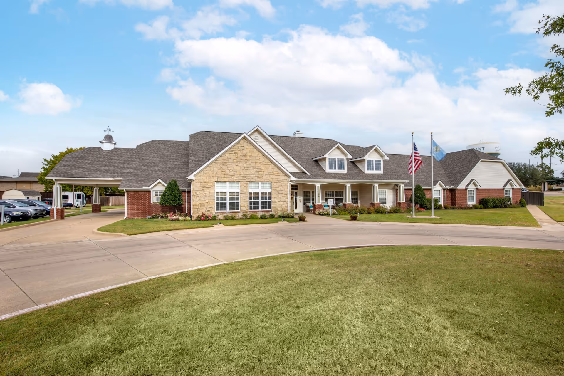 Exterior view of Oxford Springs Durant facility with a stone facade, driveway, and flagpoles.