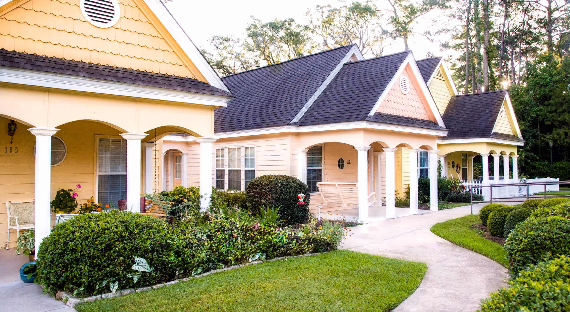 Row of pastel exterior cottages with arched porches, manicured lawn, and walkways.