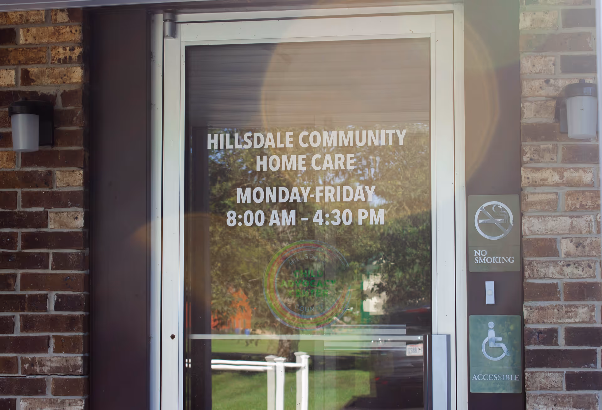 Front entrance of Hillsdale Community Home Care with glass door and posted hours.