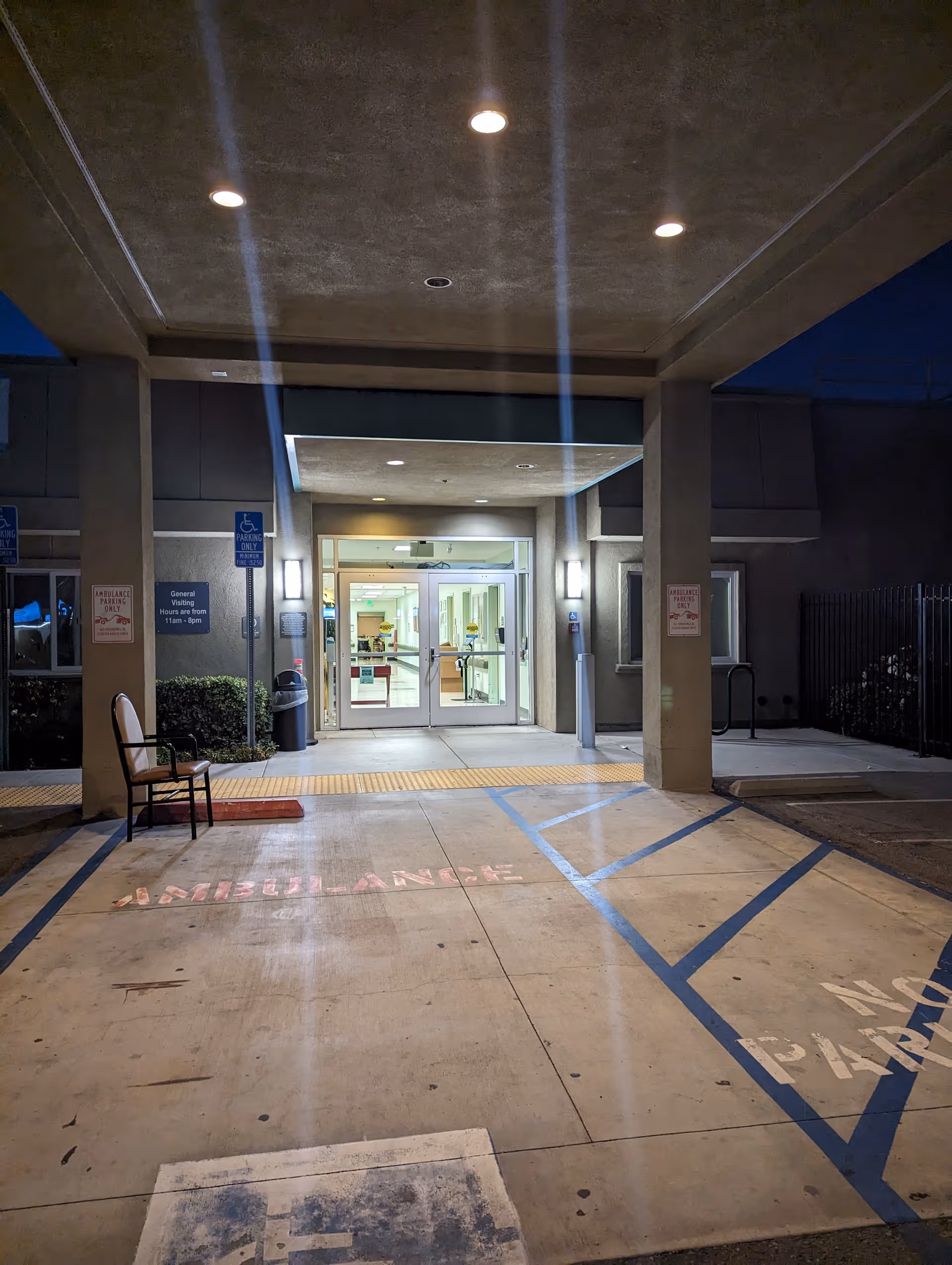 Exterior entrance of a convalescent hospital with double glass doors and handicap signs.