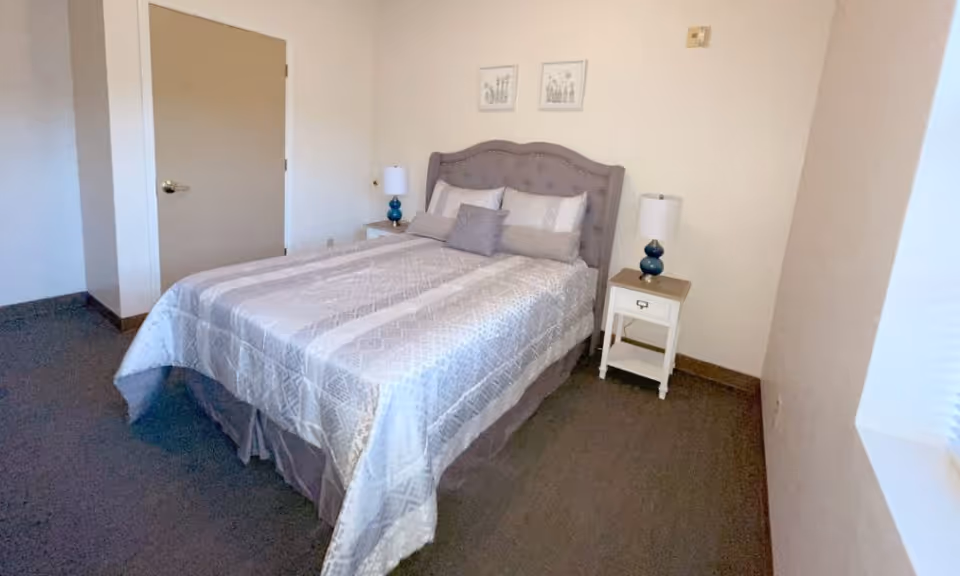 Queen bed with tufted headboard, two nightstands, and soft decor in a cozy bedroom.