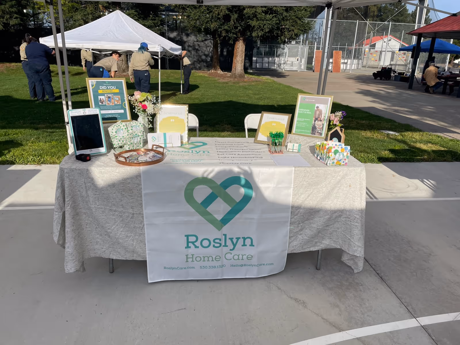 Outdoor booth with Roslyn Home Care banner and brochures on a table.