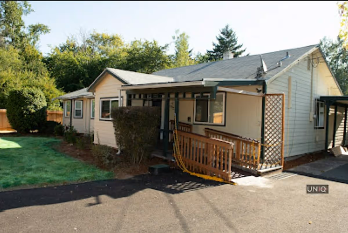 Single-story beige building with ramp and greenery, exterior view of a senior home.