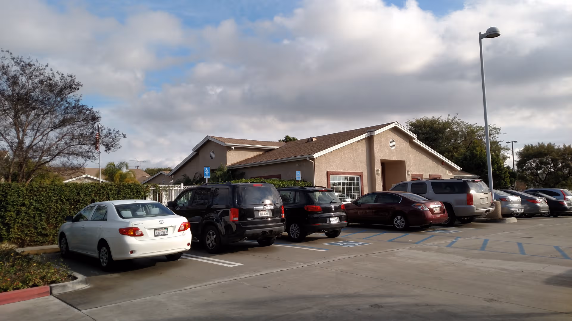 Exterior view of Ivy Terrace at Garden Grove Memory Care with parked cars in front lot.
