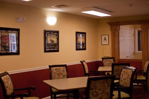 Cozy dining area with tables and patterned chairs in a memory care facility.