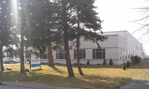 Exterior view of AmeriStaff Nursing Services building with trees and a sign in front.