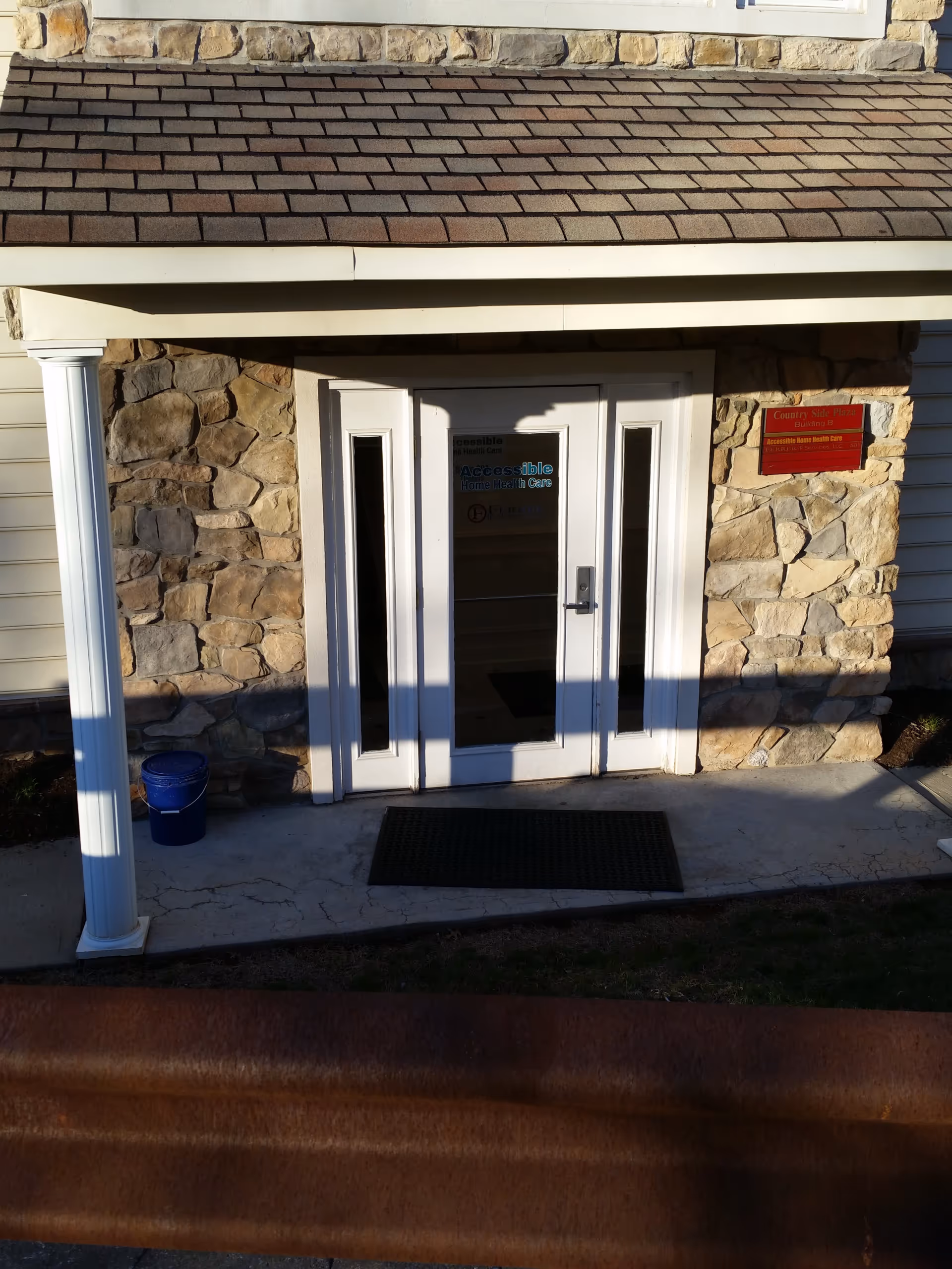 Stone exterior entrance with white double doors, columns, and a small porch.