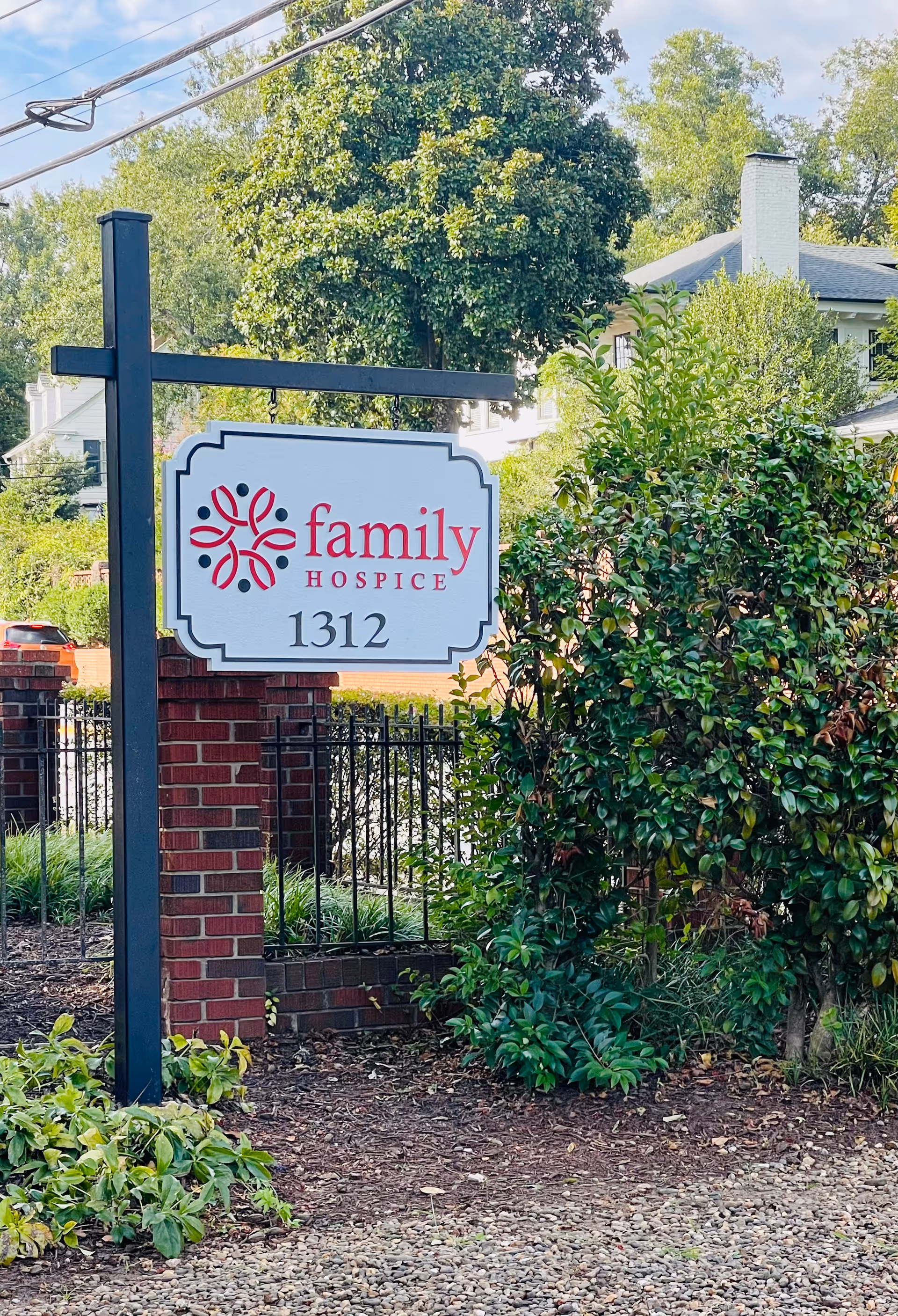 Exterior view of Family Hospice sign beside shrubbery and a brick pillar.