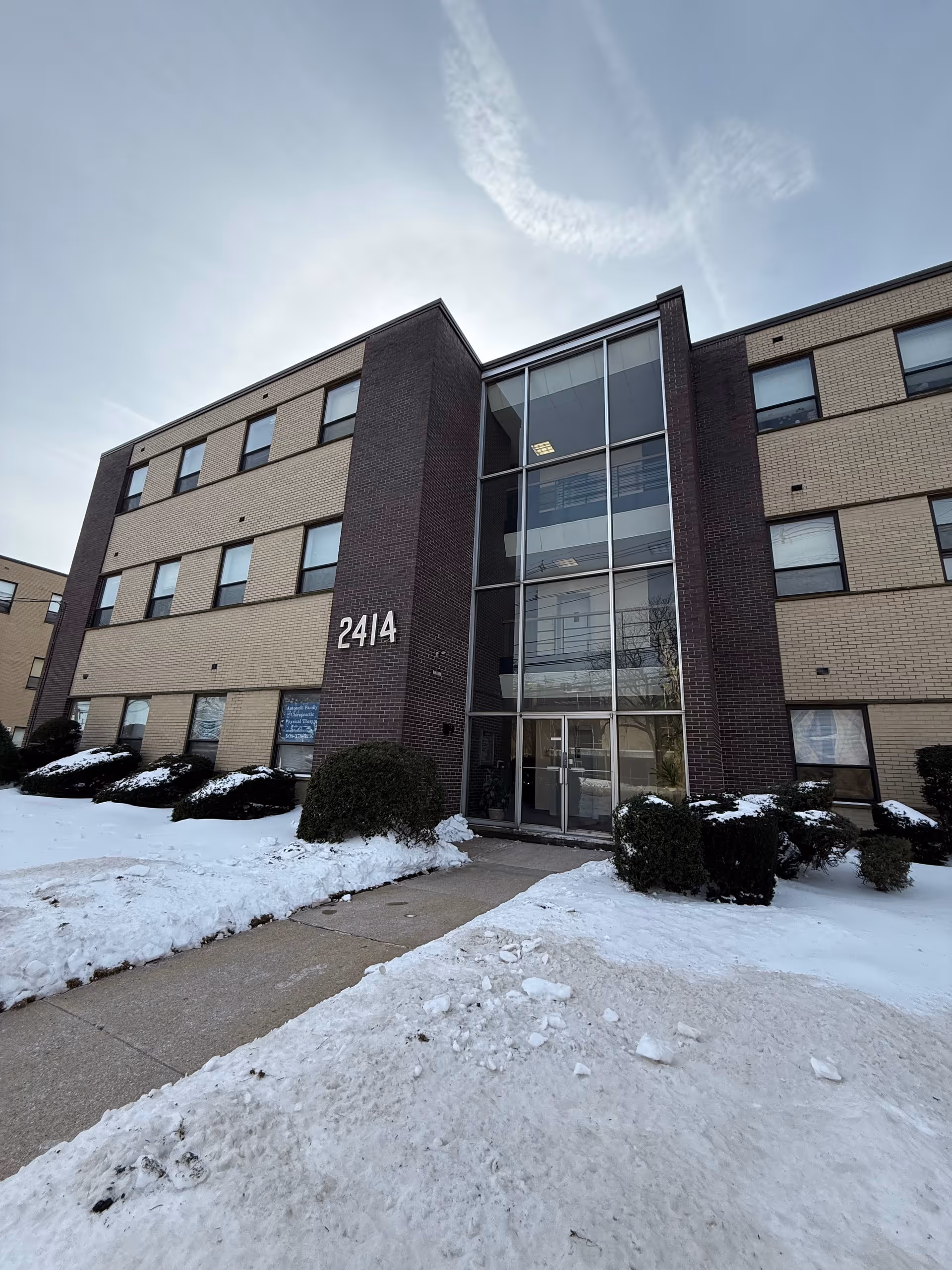 Exterior view of OnVerra Health senior living building with glass entrance and snow.