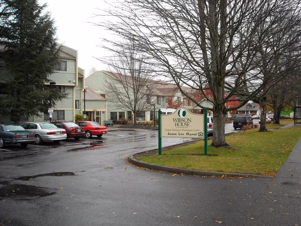 Mary-Jude Nursing Home exterior with parked cars and a sign near trees.