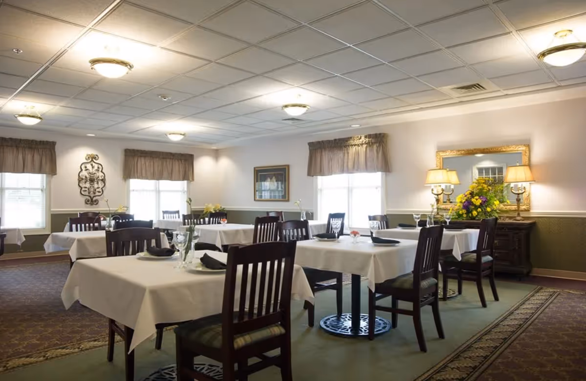 Bright dining room with tables set for meals and a decorative sideboard.