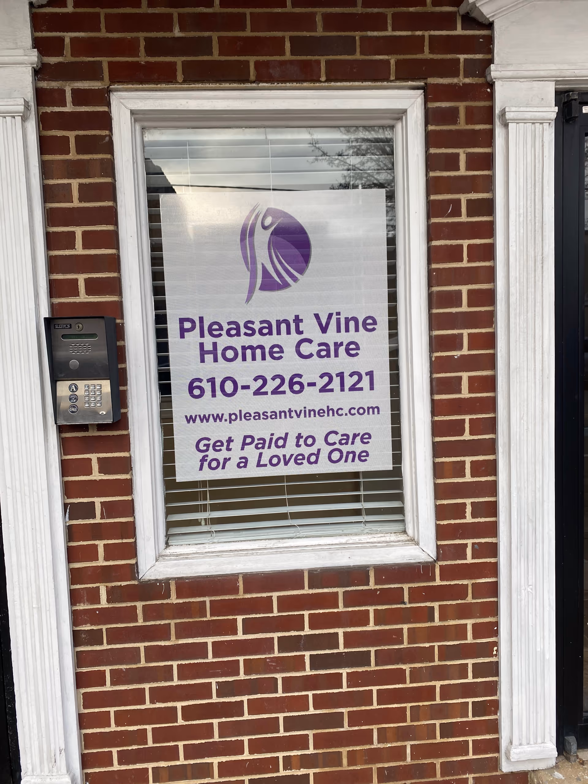 Window sign for Pleasant Vine Home Care on brick building facade
