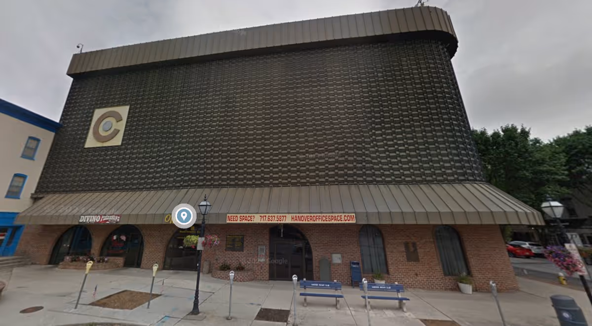 Exterior view of a brick storefront with a tall curved dark-tiled facade.