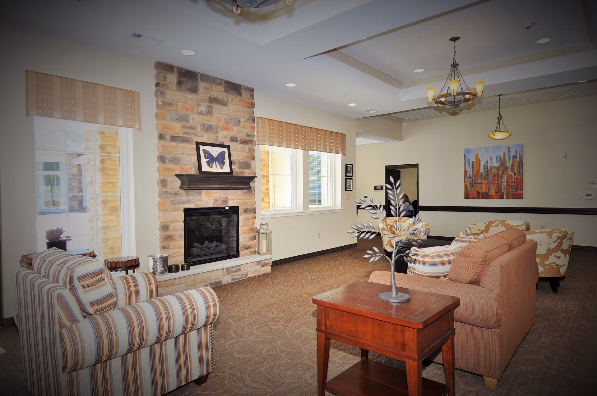 Cozy lounge area with striped chairs, sofa, fireplace, and decorative table.
