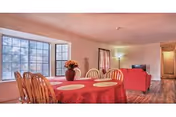 A dining area in a senior living facility with a round table, red tablecloths, and chairs.