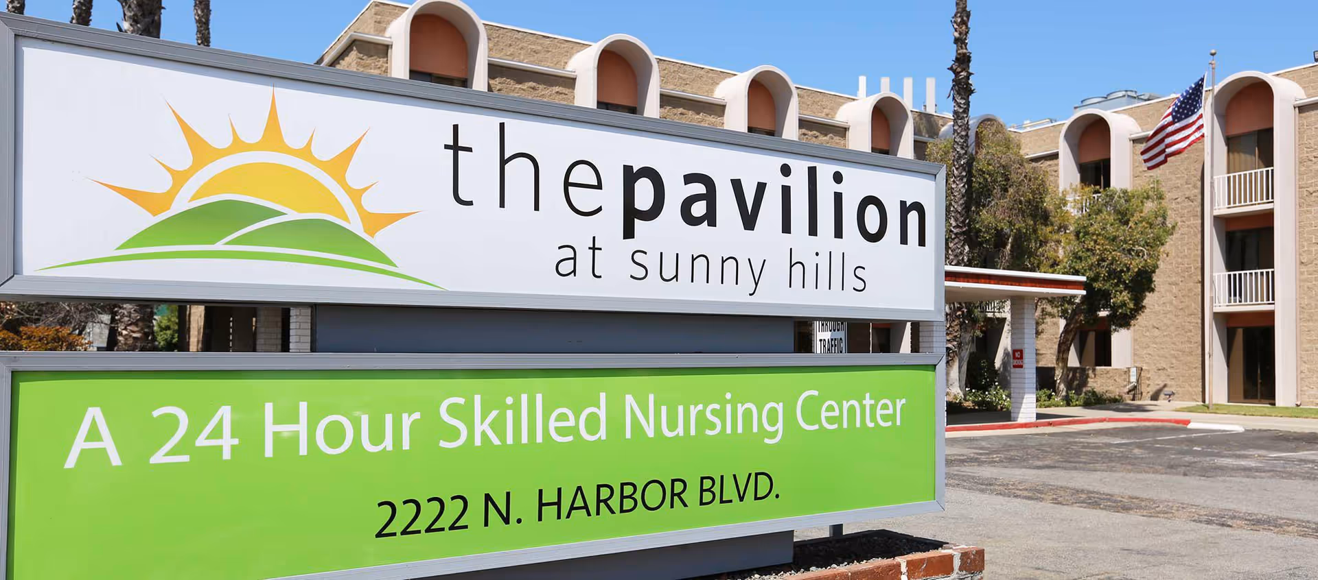 Sign reads The Pavilion at Sunny Hills with a green banner and building facade.