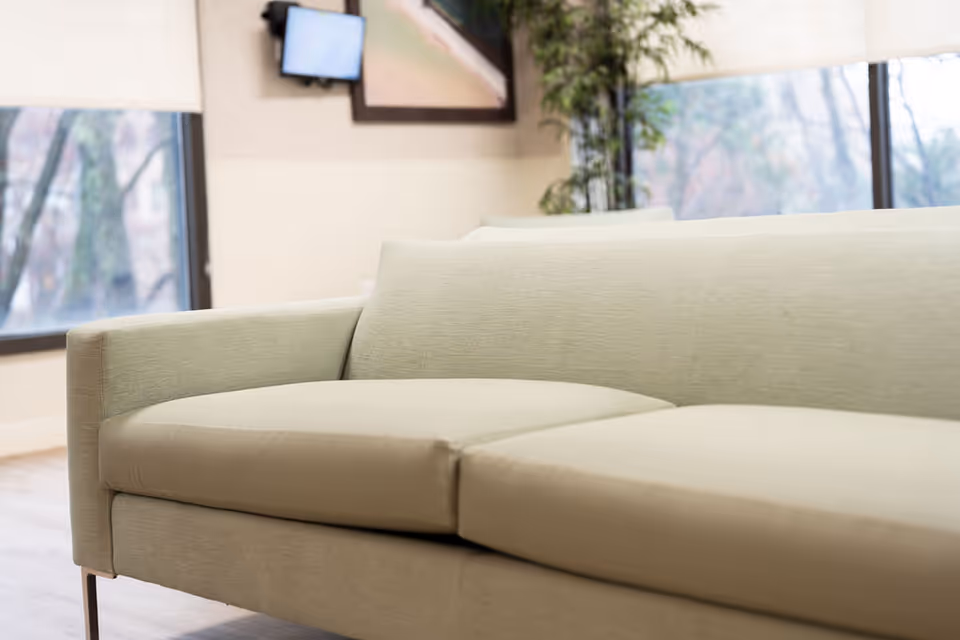 Cream-colored sofa in a bright, modern living area with large windows.