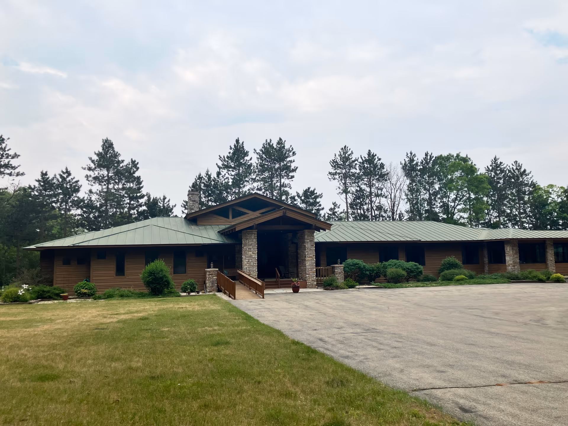Wooden single-story senior facility with stone entry pillars and a wide driveway.