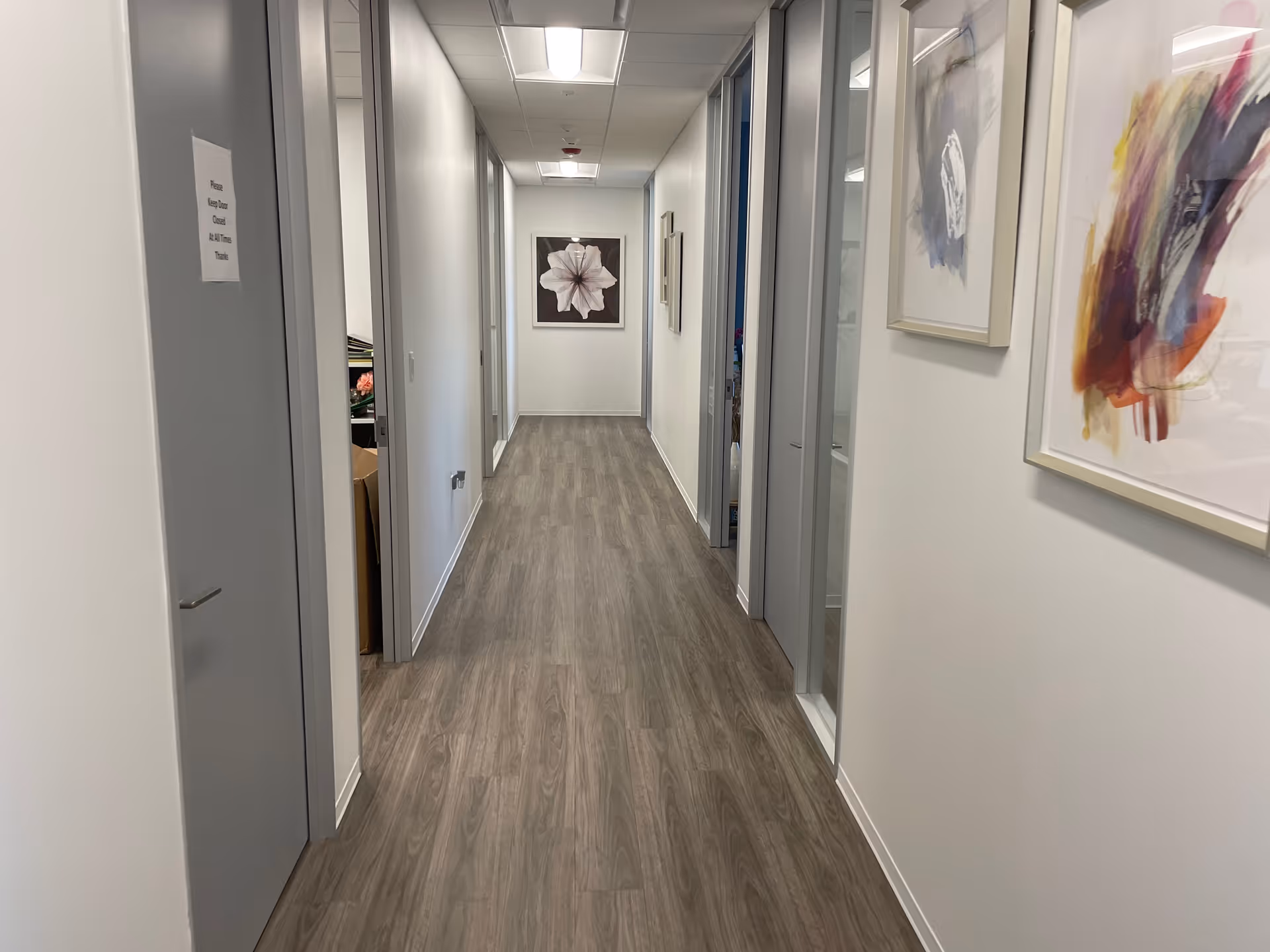 A clean, well-lit hallway in a senior living facility with framed wall art.