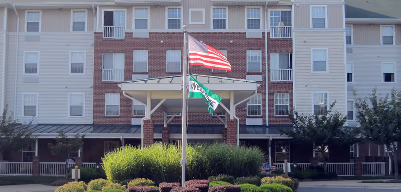 Exterior view of Churchill Senior Living building entrance with flags and landscaping.
